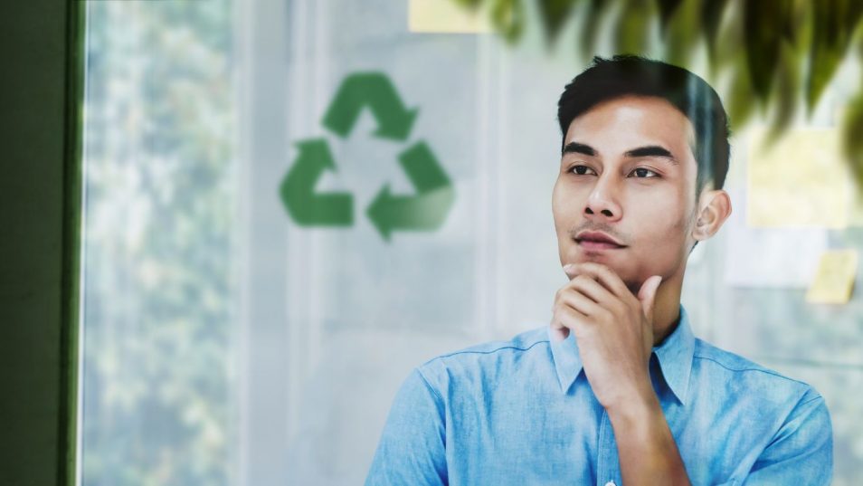 young man pensively looking at recycling symbol